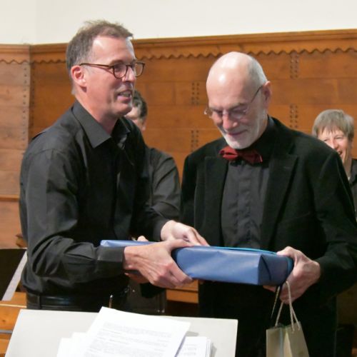 Michel Burnand reçoit en cadeau un « petit livre » de la part des musiciens de Dix de cuivre